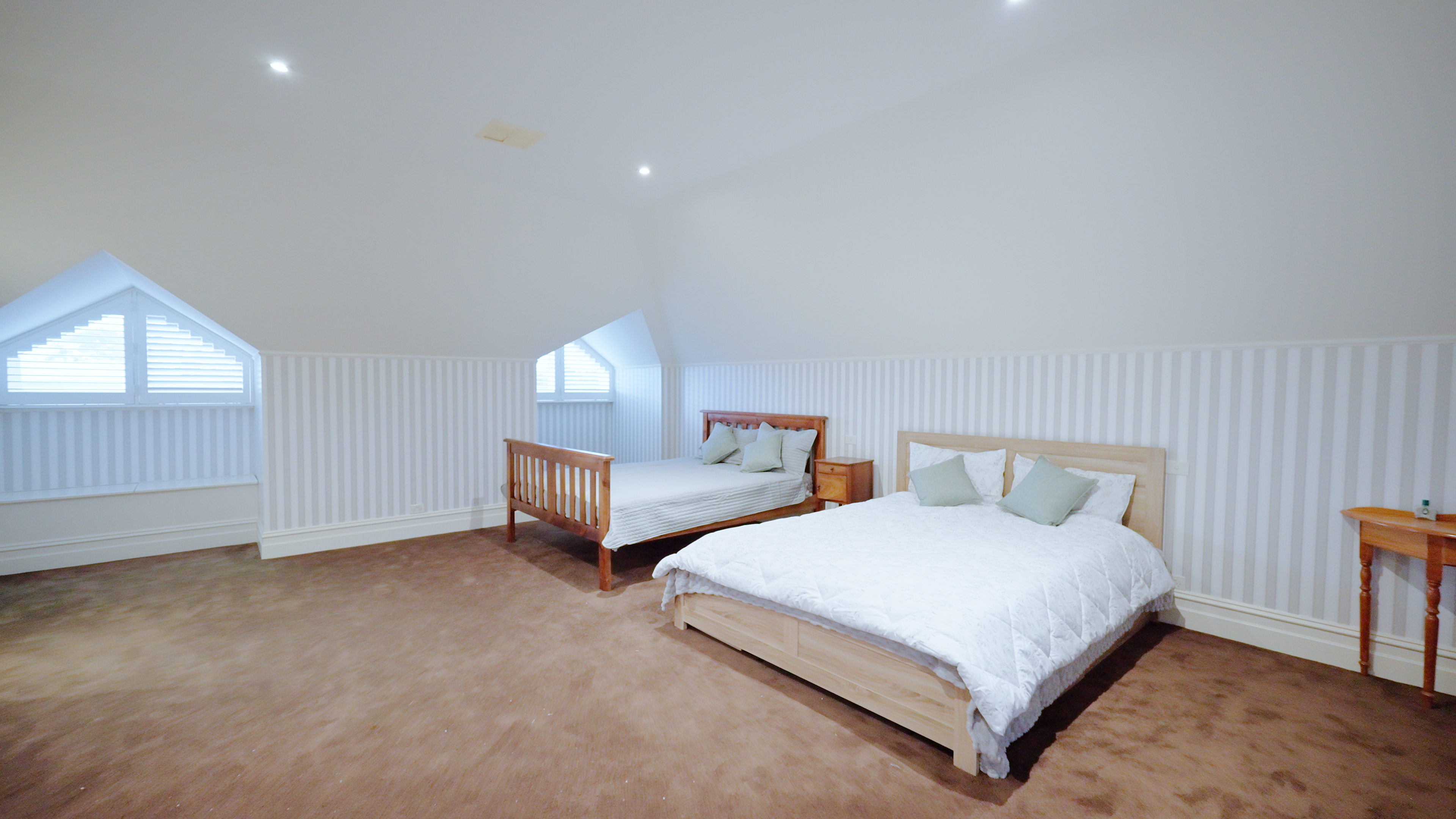 Charming attic room with dormer windows and striped wallpaper